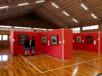 会場の一隅　赤いパネルに展示された風景画を生徒二人が鑑賞する様子