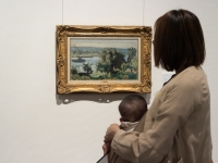 赤ちゃんを抱っこした保護者が、風景画を鑑賞する様子