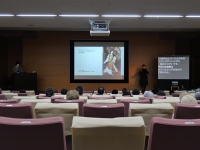 講堂での講演会の様子　中央のスクリーンには作品画像が投影され、その右手で手話通訳が行われている。通訳者の右には要約筆記の文字を映すスクリーンが設置される。