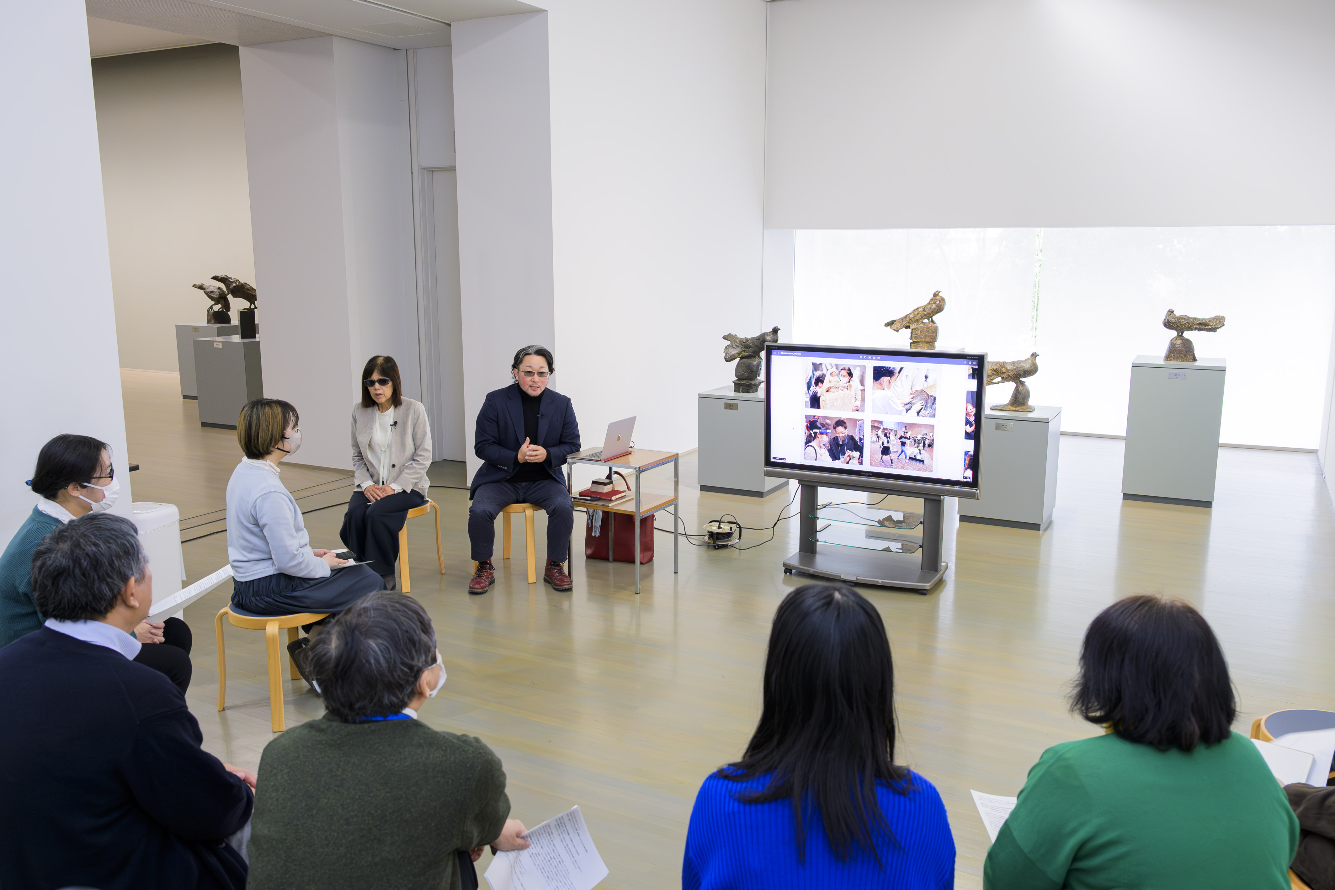 講師のレクチャー風景。展示室内で話す講師の周りに参加者が座る。