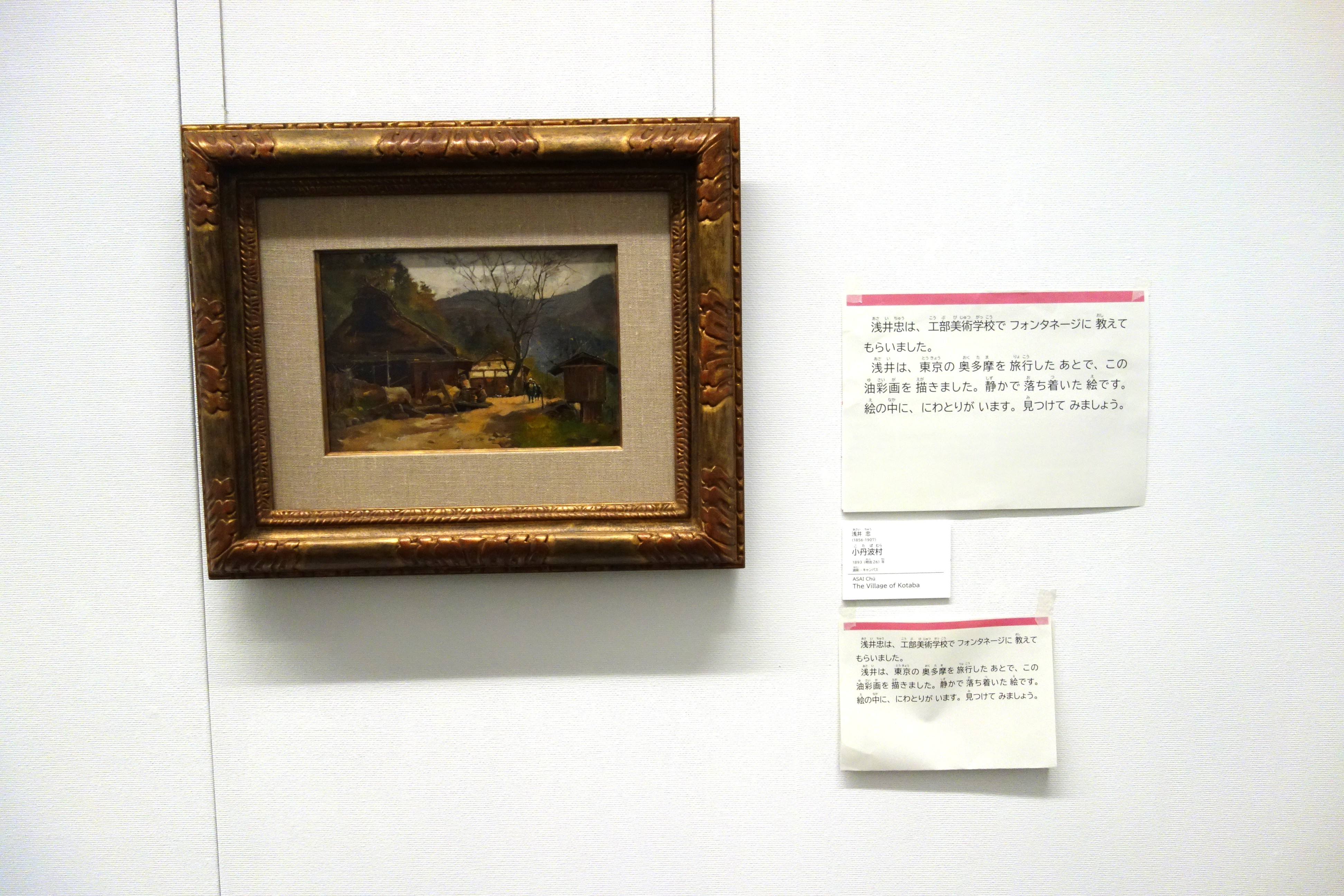 絵画の隣に、説明の書かれた大きさの違う紙やパネルが掲示されている